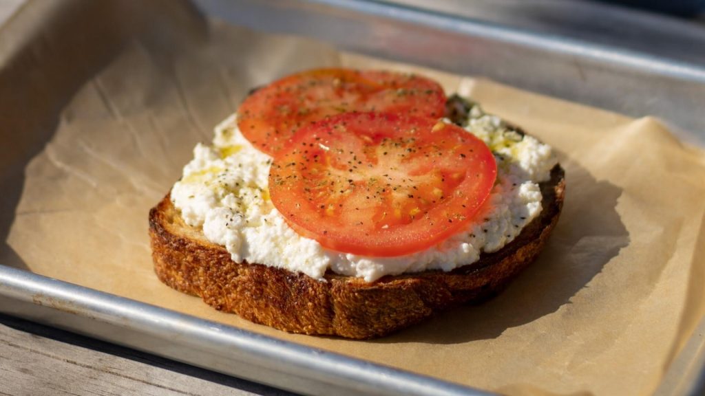 Sliced toast topped with a generous spread of vegan ricotta cheese, a delectable plant-based option.